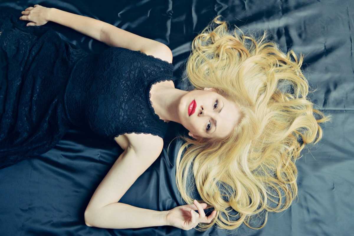 donna stesa con i capelli sparsi sul letto