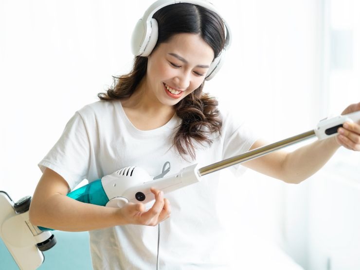 donna co cuffie che ascolta musica e suona una scopa elettrica