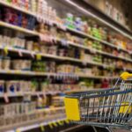 carrello del supermercato e scaffali pieni di cibo in scatola
