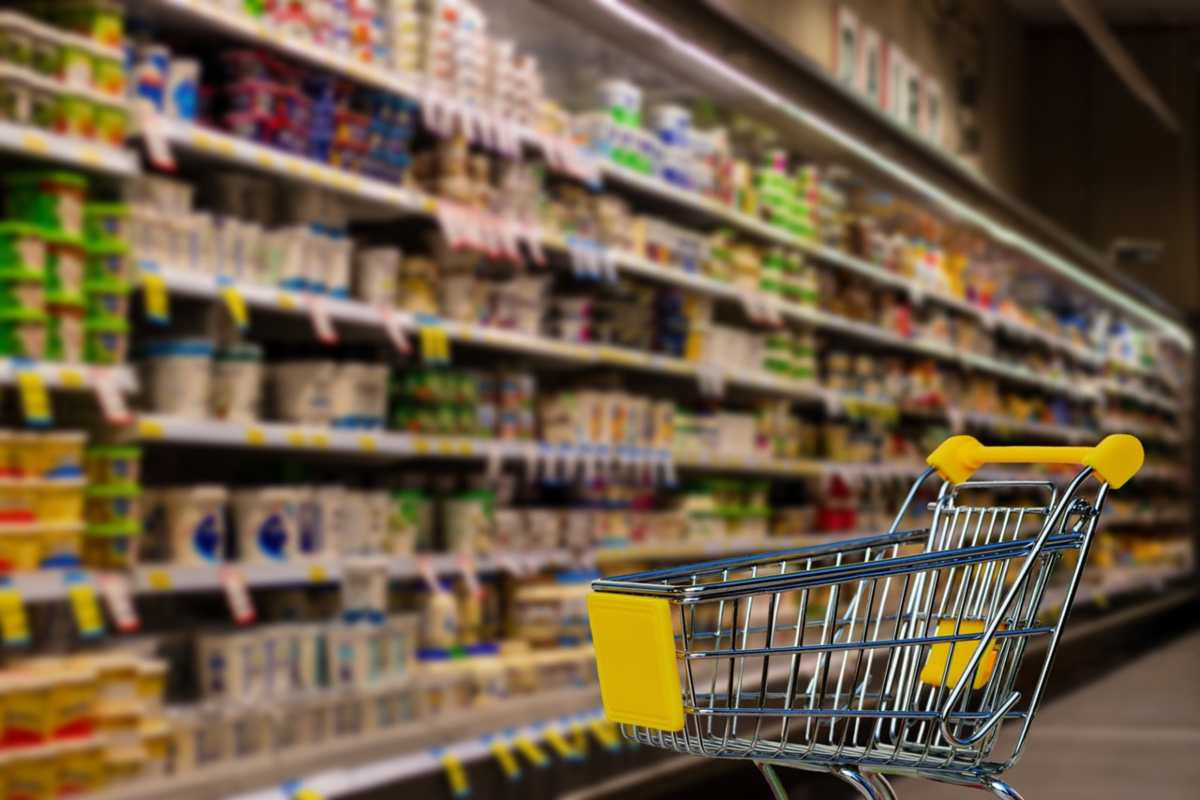 carrello del supermercato e scaffali pieni di cibo in scatola