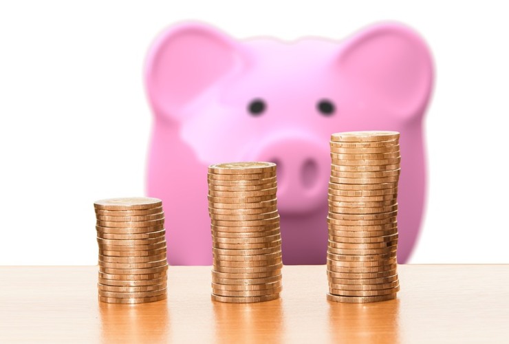 salvadanaio a forma di maialino rosa e pile di monete