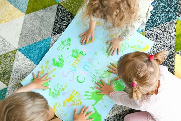 Bambini giovano su un cartellone con le loro mani colorate