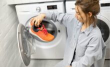 donna con scarpe da ginnastica in mano prese dalla lavatrice