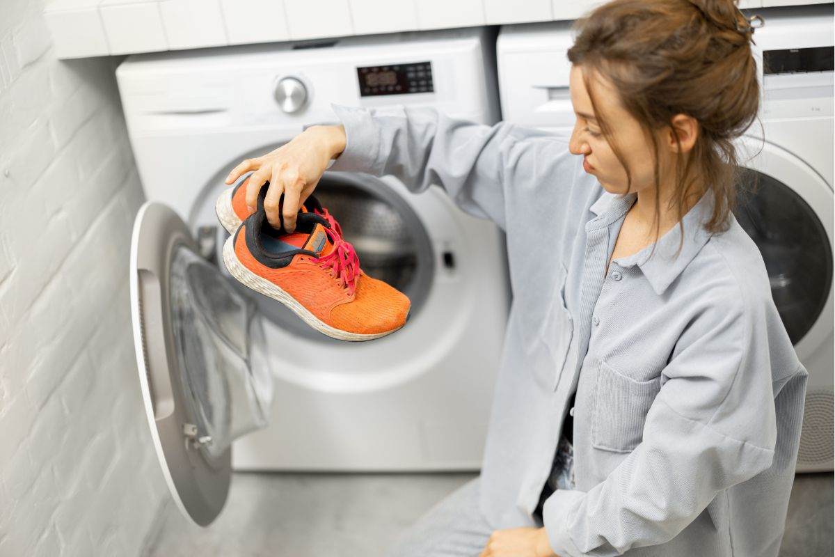 donna con scarpe da ginnastica in mano prese dalla lavatrice