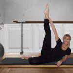 donna distesa su un tappetino da yoga con una gamba distesa in alto