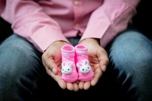 uomo con un paio di scarpine rosa da neonato in mano